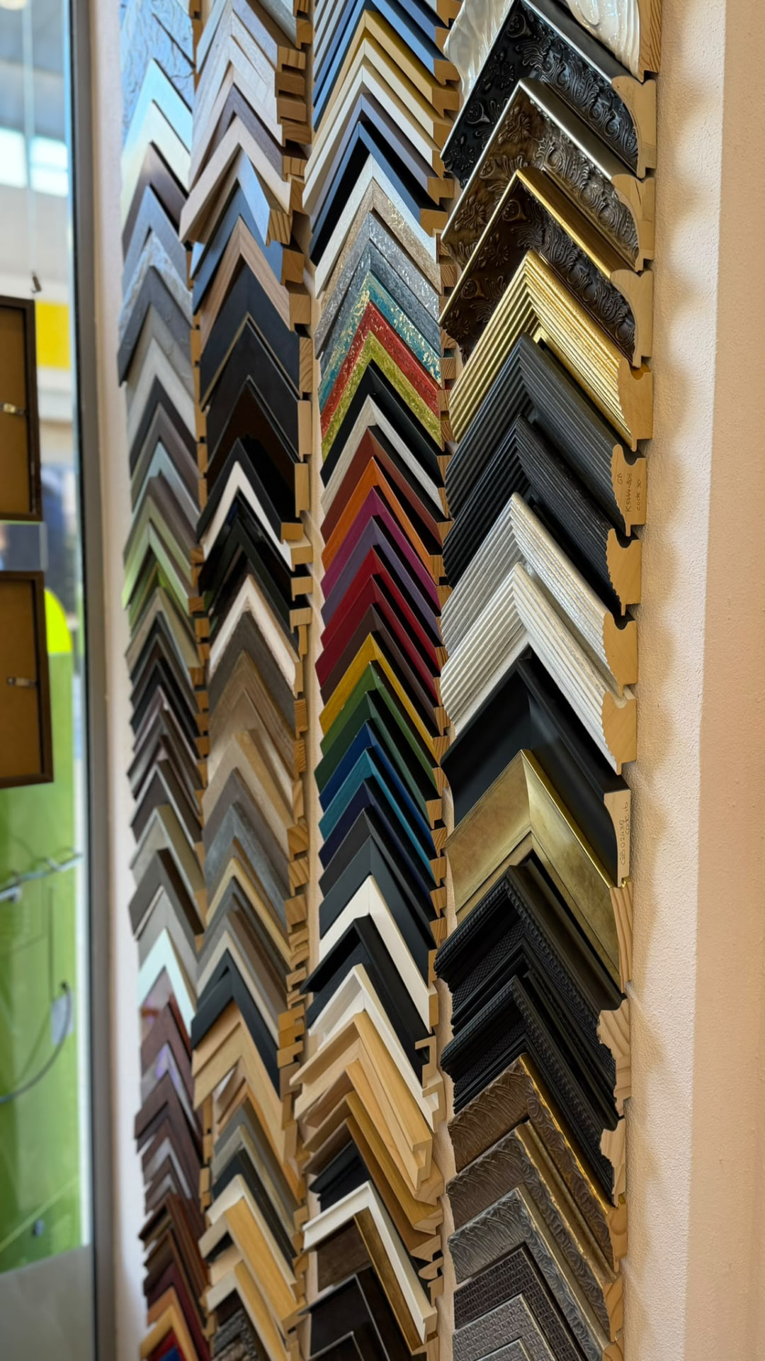 Wand vol houten en metalen lijstenprofielen in verschillende kleuren en stijlen